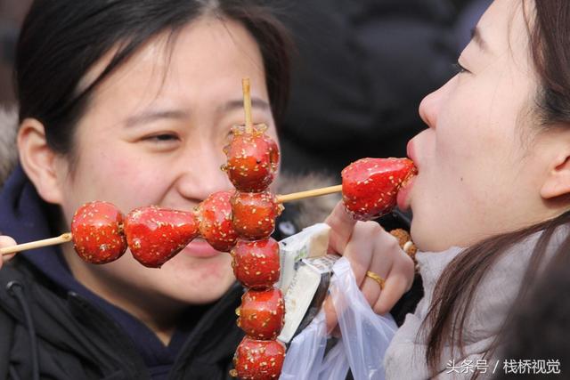 美食谁不爱？青岛庙会饕餮百态看得流口水，美女吃糖球不颇形象