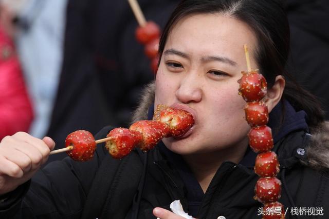 美食谁不爱？青岛庙会饕餮百态看得流口水，美女吃糖球不颇形象